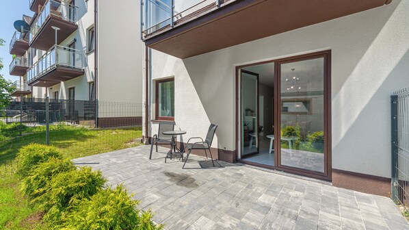 A residential building with a balcony, a small patio with a table and chairs, and a garden area. - Sun & Snow Baltic Nova (Wladyslawowo)