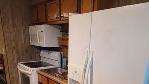 Una cocina con armarios de madera, un refrigerador blanco, un microondas, una estufa y un lavavajillas.