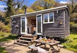 A rustic wooden cabin with a dining area set up outside.