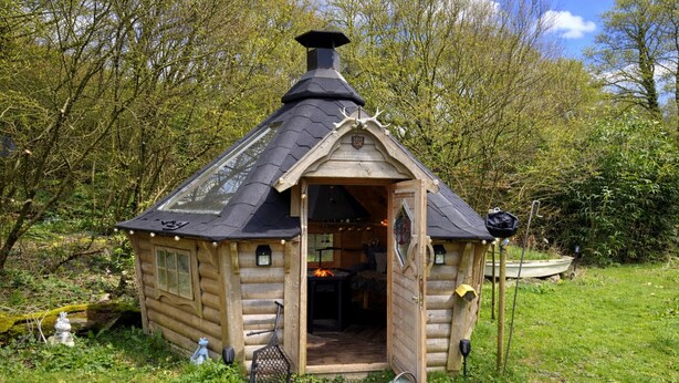 A wooden cabin with a chimney, a door leading inside, and a small porch area.