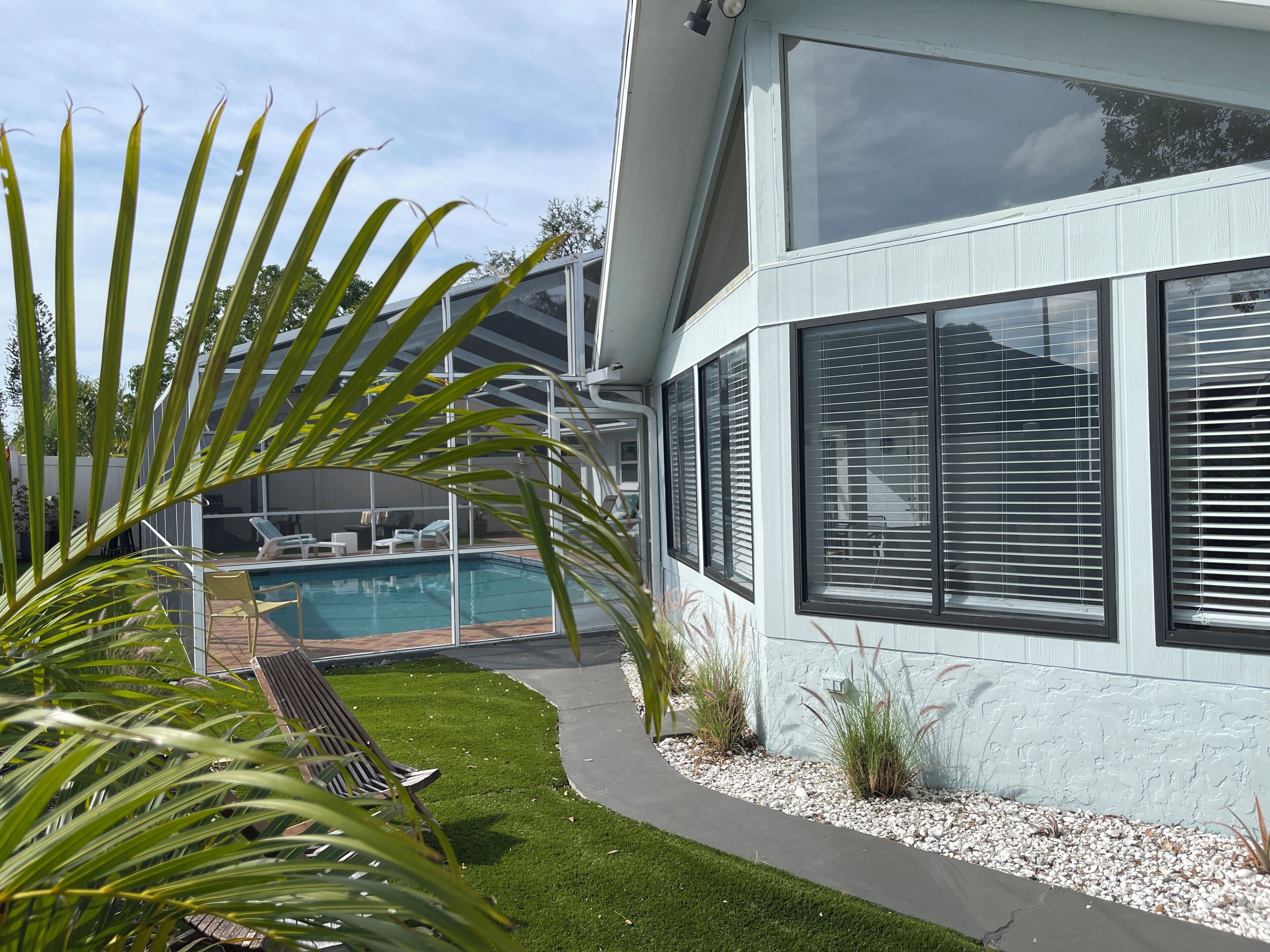 Una casa moderna con piscina, patio con panchina e prato curato.