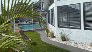 Uma casa moderna com piscina, um alpendre com banco e um gramado bem cuidado.