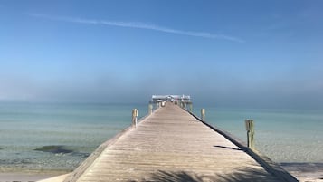 Un molo di legno che si protende in acque calme sotto un cielo sereno.