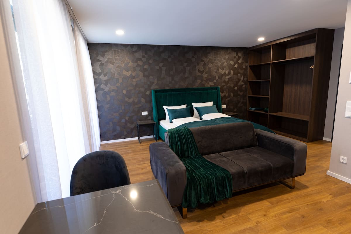 Un dormitorio moderno con cama, sofá, mesa y estanterías empotradas.