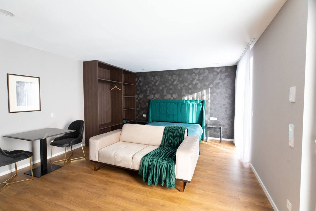 Un dormitorio moderno con sofá, escritorio y armario.