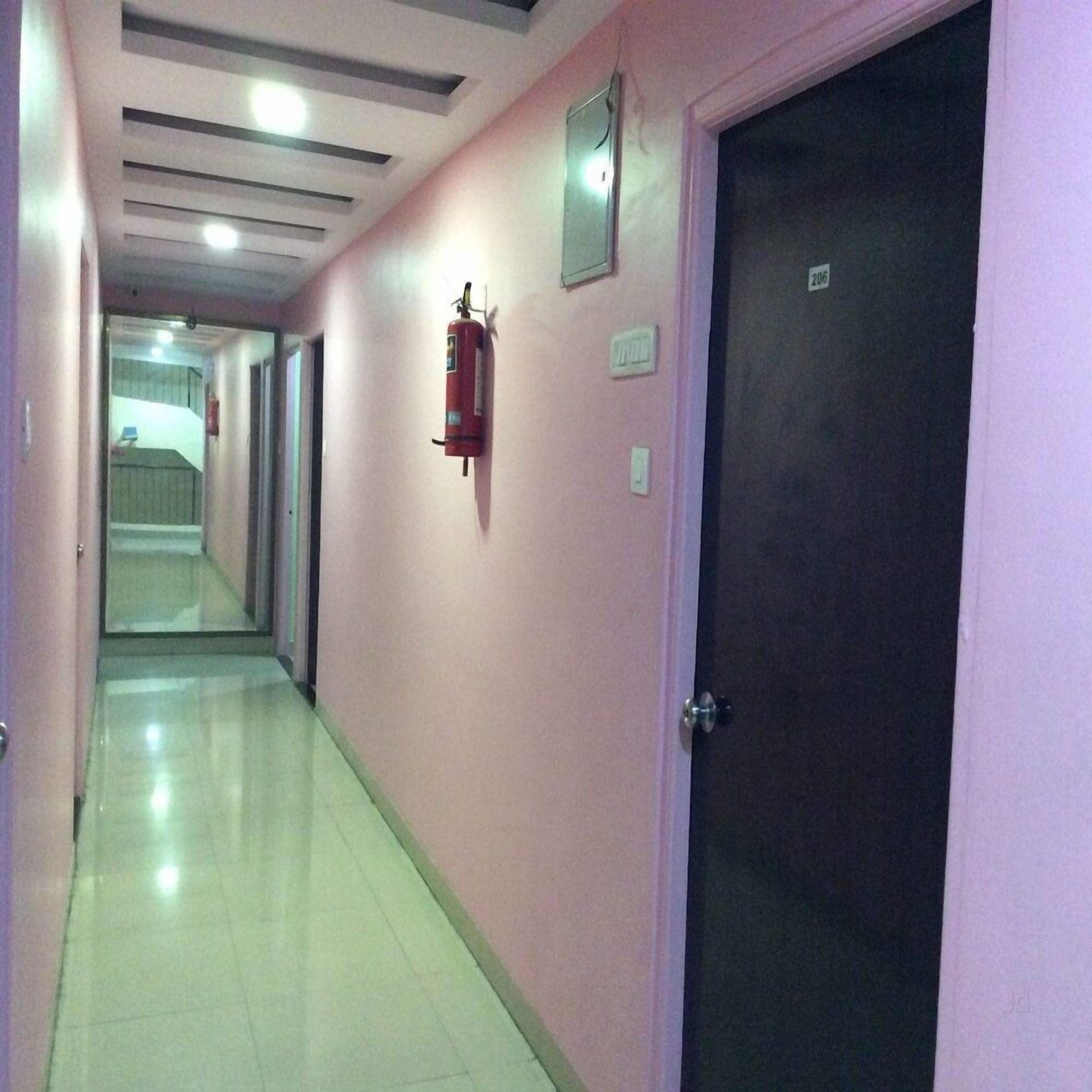 Um corredor com um extintor preso na parede, uma porta com o símbolo de número e chão de azulejos.