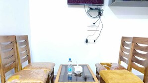 Una habitación con una mesa de madera y cuatro sillas, una botella de agua y un enchufe en la pared.