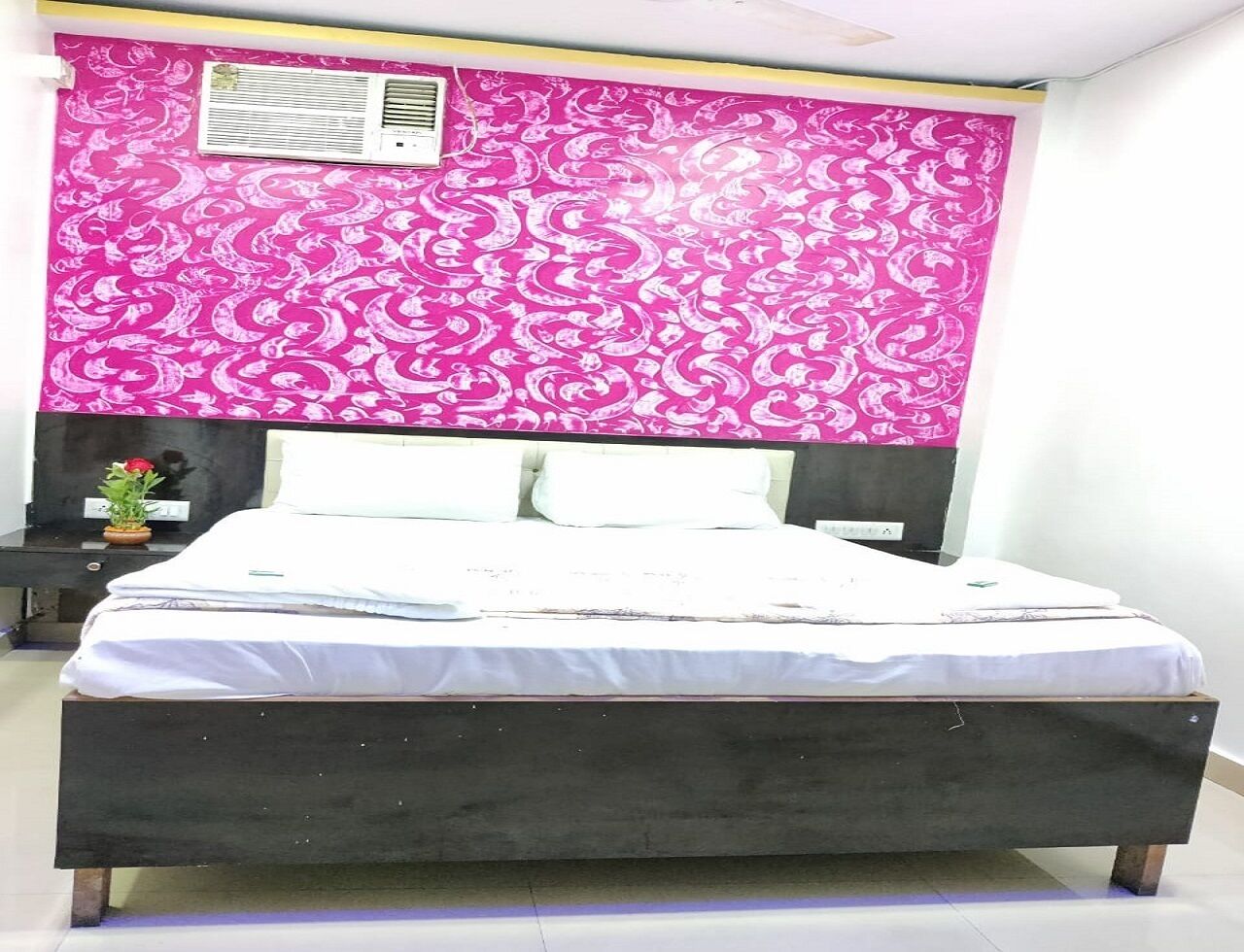 Un dormitorio con una cama, una mesita de noche y un aire acondicionado instalado en la pared.