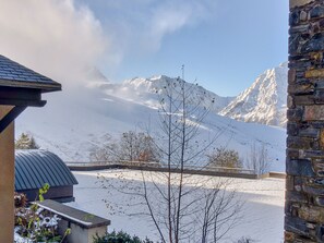 A snow-covered mountain landscape with a stone building and a metal roof structure in the foreground.