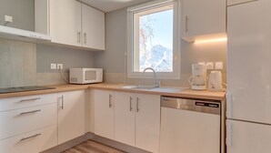 Una cocina moderna con armarios blancos, microondas, cafetera y lavavajillas.