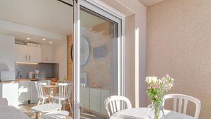 Una cocina moderna con armarios blancos y una zona de comedor con una puerta de vidrio que da a un espacio exterior.