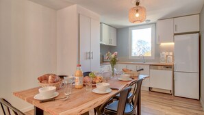 Una cocina moderna con una mesa de comedor de madera, sillas y una variedad de alimentos para el desayuno.