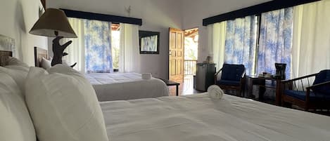 Une chambre spacieuse avec un grand lit, un bureau et une chaise. Il y a une fenêtre avec des rideaux et une vue sur l’extérieur.