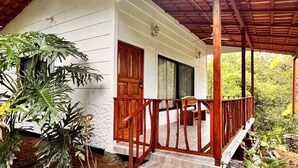 A wooden house with a porch, a wooden door, and a sign that reads "Heliconia Cottage". - Blue Banyan Inn (Naranjito)