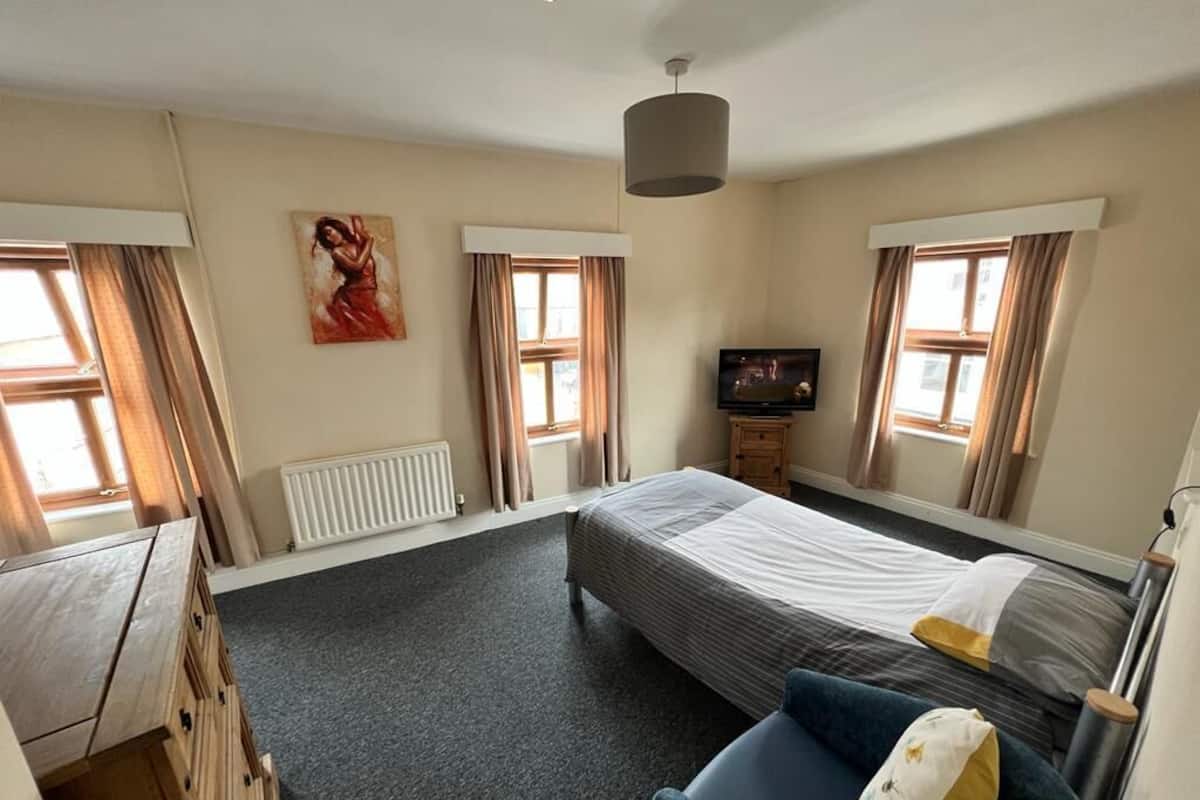 A hotel room with a bed, a TV, a desk, and a chair.