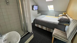 A bedroom with a bed, a chair, a TV, a shower, and skylights. - The Hoptimist  (Stockton-on-Tees)
