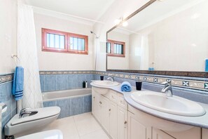 Een bad/douchecombinatie, een bidet, handdoeken