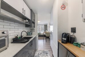 A modern kitchen with a built-in oven, a coffee machine, and a no-smoking sign.