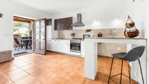 A modern kitchen with white cabinets, a central island, and a dining area with chairs.