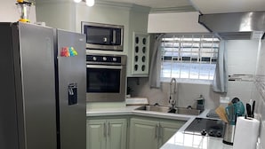 Een compacte keuken met een centraal eiland, een koelkast, een magnetron en een fornuis.