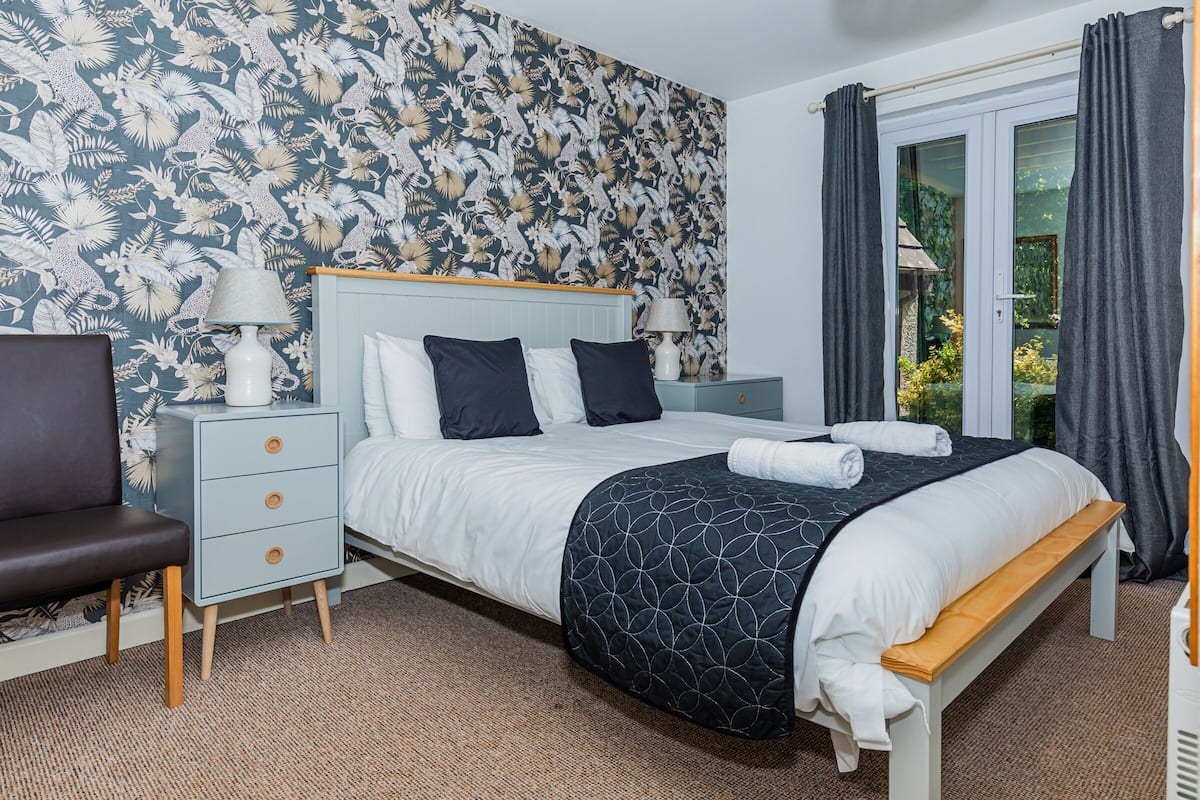 A bedroom with a bed, bedside tables, a chair, and a window with curtains.