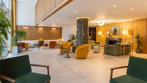 A spacious lobby with a high ceiling, wooden paneling, and a central column. There are multiple seating areas with chairs and sofas, and a fireplace with a black mantle. - Best Western Plus Casablanca City Center (Casablanca)