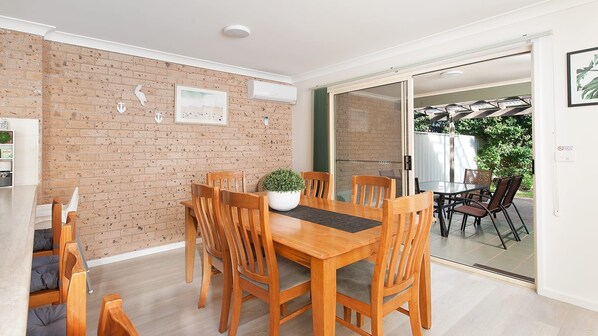 Een eetgedeelte met een bakstenen muur, een houten tafel en stoelen.
