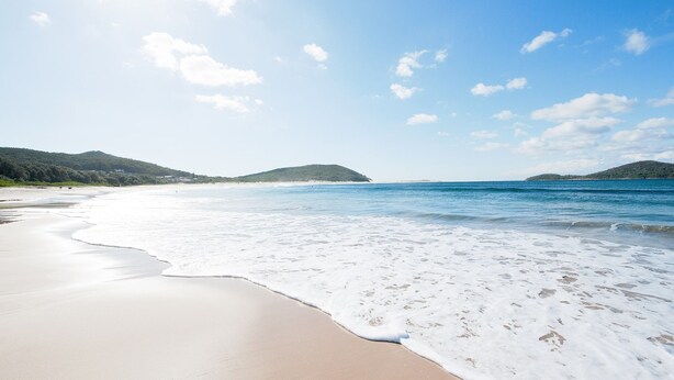 A beach with clear skies, gentle waves, and distant hills. - Bombora Walking Distance to Fingal Beach- Farm Rd, Fingal Bay (Fingal Bay)