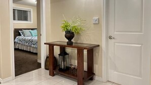 Un couloir avec une console en bois, une plante en pot, une lanterne et une porte.