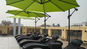 A rooftop lounge area with multiple lounge chairs and green umbrellas. - Rosemond Al Hamra (Jeddah)