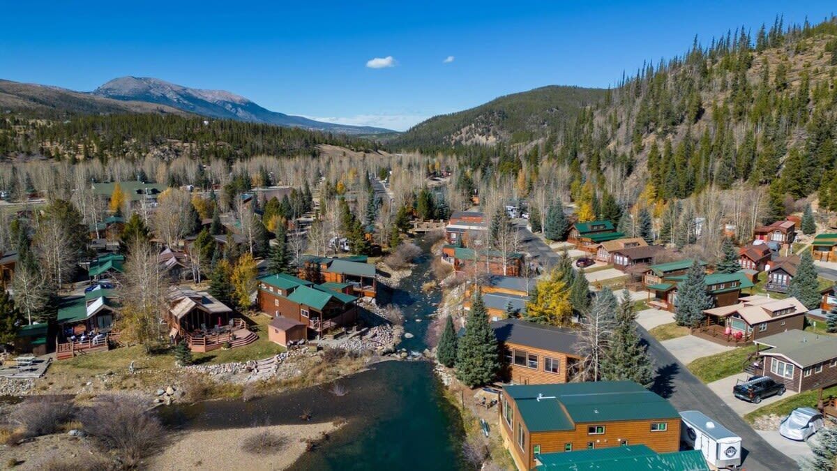 A small town with a river, surrounded by mountains and dense forests.