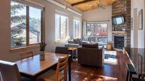 A spacious living room with a fireplace, large windows, and a balcony. - 2BR Riverside Cabin - Near Trails w/Hot Tub Access (Breckenridge)