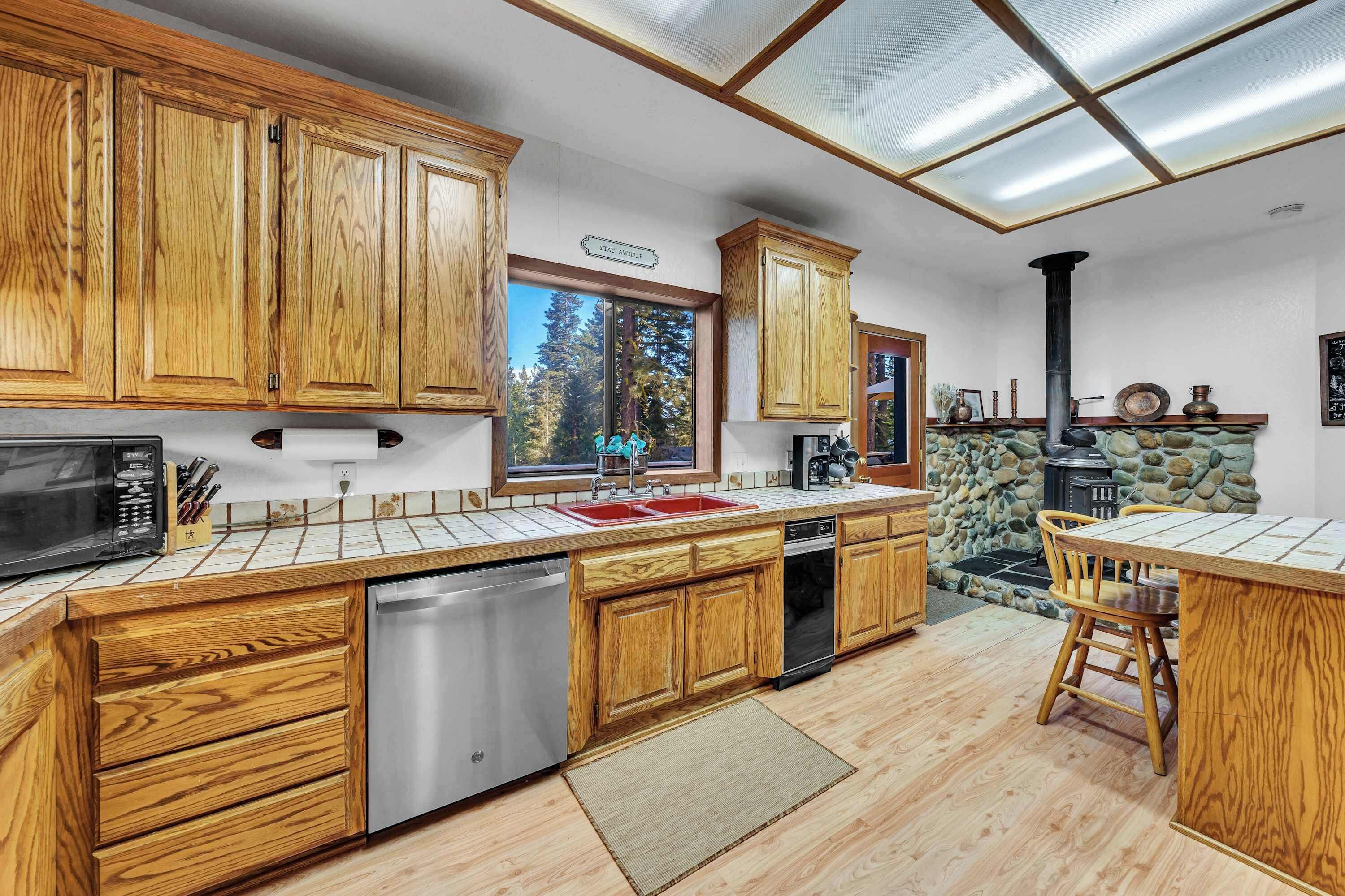 A kitchen with wooden cabinets, a dishwasher, a sink, and a stone wall.