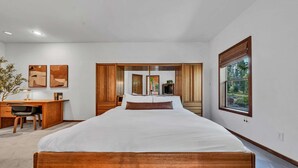 A modern bedroom with a large bed, wooden headboard, a desk with a chair, and a window with blinds. - Talmont Pines 4BR Retreat with HOA Beach Access! (Tahoe City)