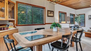 A spacious dining area with a large wooden table, black chairs, and a glass-top centerpiece.