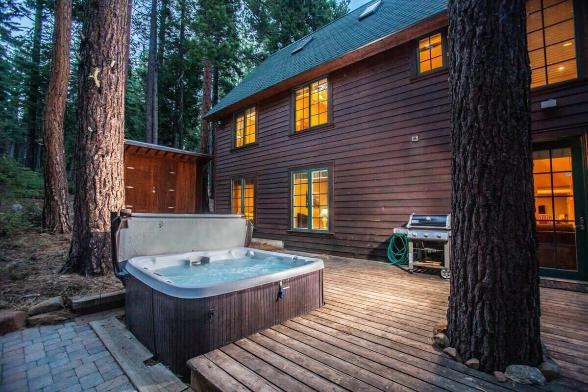 A wooden cabin with a hot tub and a grill on the deck.