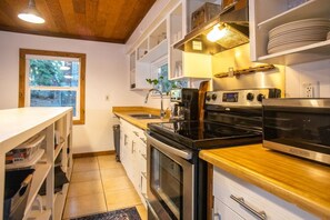 Una cocina con encimera de madera, electrodomésticos de acero inoxidable y muebles de color blanco.