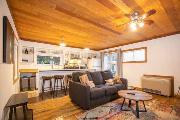 A cozy living room with a sofa, a coffee table, and a kitchen in the background.