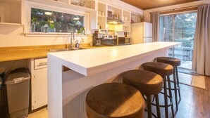 Una cocina con una isla central, taburetes, una ventana y vistas al exterior.