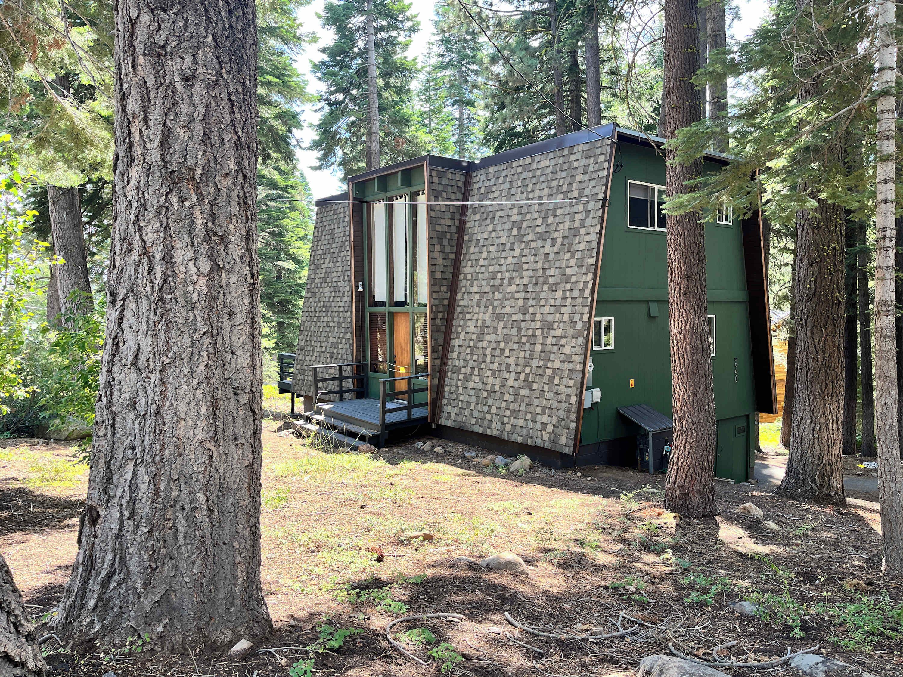 A cabin with a stone exterior, a wooden deck, and a green door.