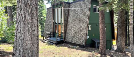 A cabin with a stone exterior, a wooden deck, and a green door.