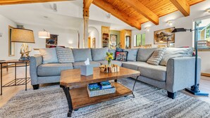 Ein gemütliches Wohnzimmer mit einem Ecksofa, einem Holztisch und einem Teppich.