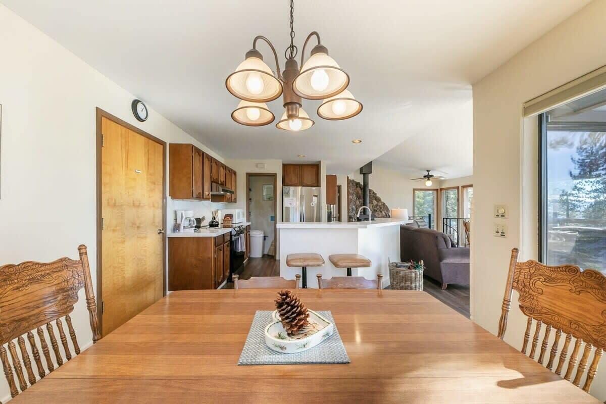 Een eethoek met een houten tafel, stoelen en een dennenappel als middelpunt.