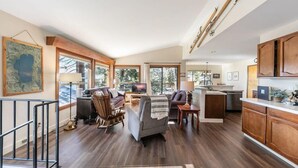 A spacious living area with a fireplace, a dining area, and a kitchen with wooden cabinets. - Tahoe Vista Retreat with Lake View- Walk to beach! (Tahoe Vista)