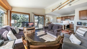 A spacious living room with a large window, a television, and a fireplace. - Tahoe Vista Retreat with Lake View- Walk to beach! (Tahoe Vista)
