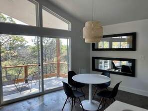 Enjoy meals in this dining area with a round table and six chairs, surrounded by floor-to-ceiling windows and a view of the outdoor deck.