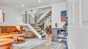 Una sala de estar moderna con una escalera, sofá de cuero, mesa de centro y alfombra.