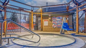 Zona de jacuzzi con un cartel de seguridad, una silla de salvavidas y un letrero de seguridad para la piscina.