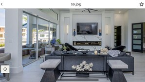 Ein modernes Wohnzimmer mit einem großen Sofa, einem Couchtisch und einem flachbildfernseher an der Wand.