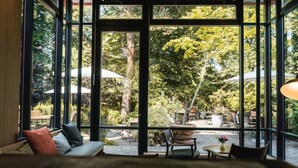A room with large windows, a bed, and a view of an outdoor patio with tables and chairs. - Wedina Serviced Apartments (Hamburg)